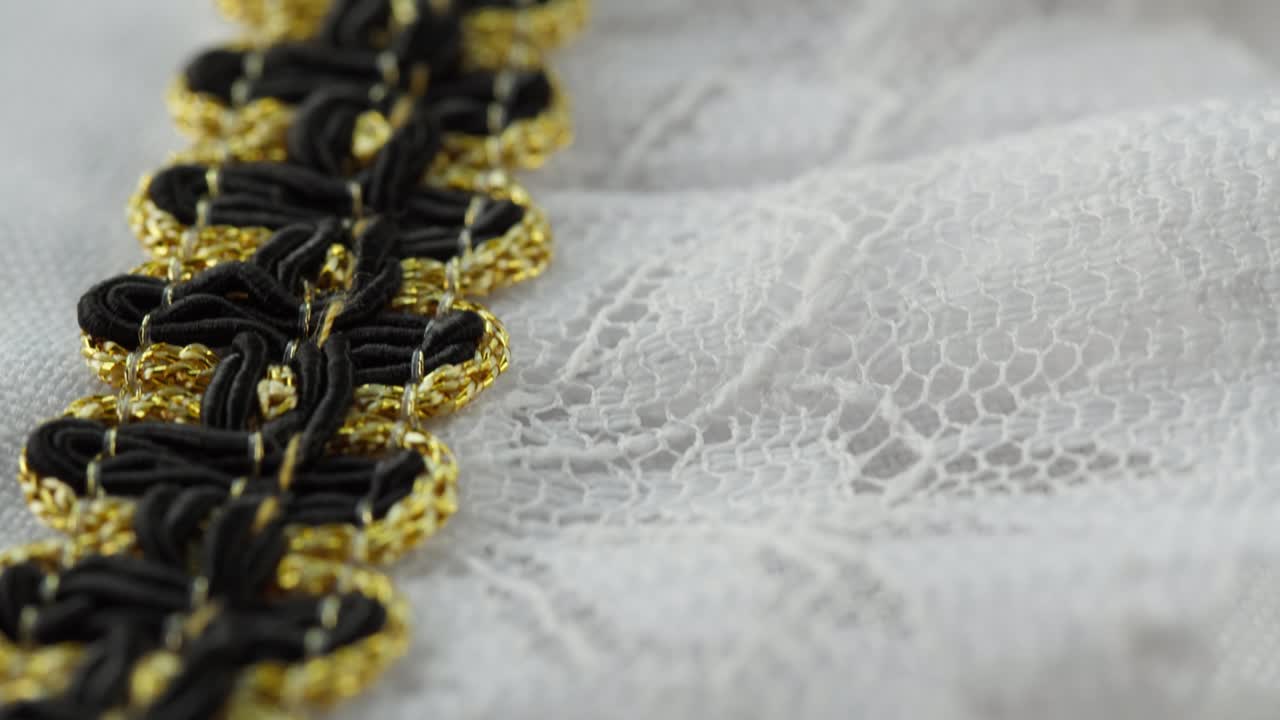 encaje blanco con decoración negra y dorada de primer plano. coser un vestido de novia. guipure ligero. sastrería hecha a mano, concepto de ropa profesional. fondo abstracto