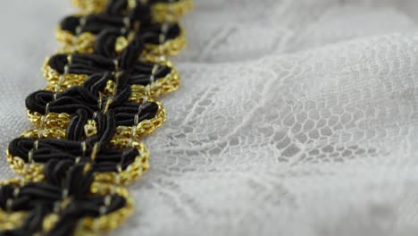 white lace with black and golden decor close-up. sewing a wedding dress. light guipure. handmade tailoring, professional clothing concept. abstract background