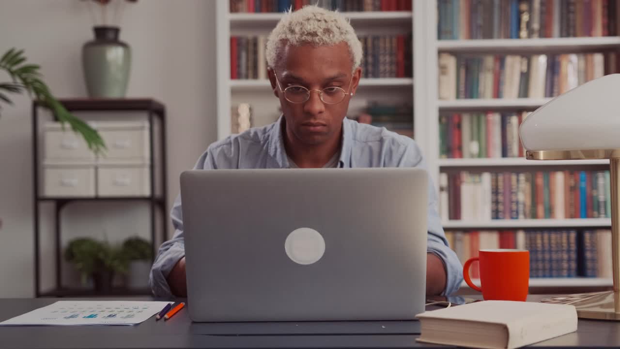 Confident african american young man opens and start using laptop at home office