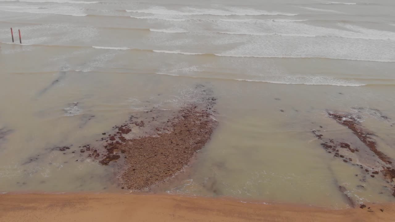 Ocean waves breaking on Allana Gadoor Village Beach under a cloudy sky
