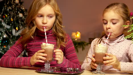 girls drink hot chocolate through a straw