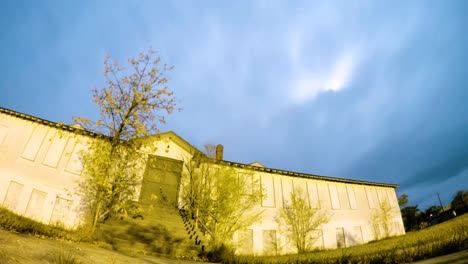 NIGHT-LAPSE---Clouds-fly-by-fast-over-a-old-abandoned-hospital-at-night