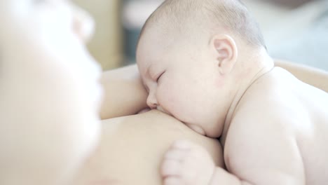 mother breastfeeds her two-month-old newborn baby, that is almost sleeping and fixes his latching mouth position before the baby pulls away