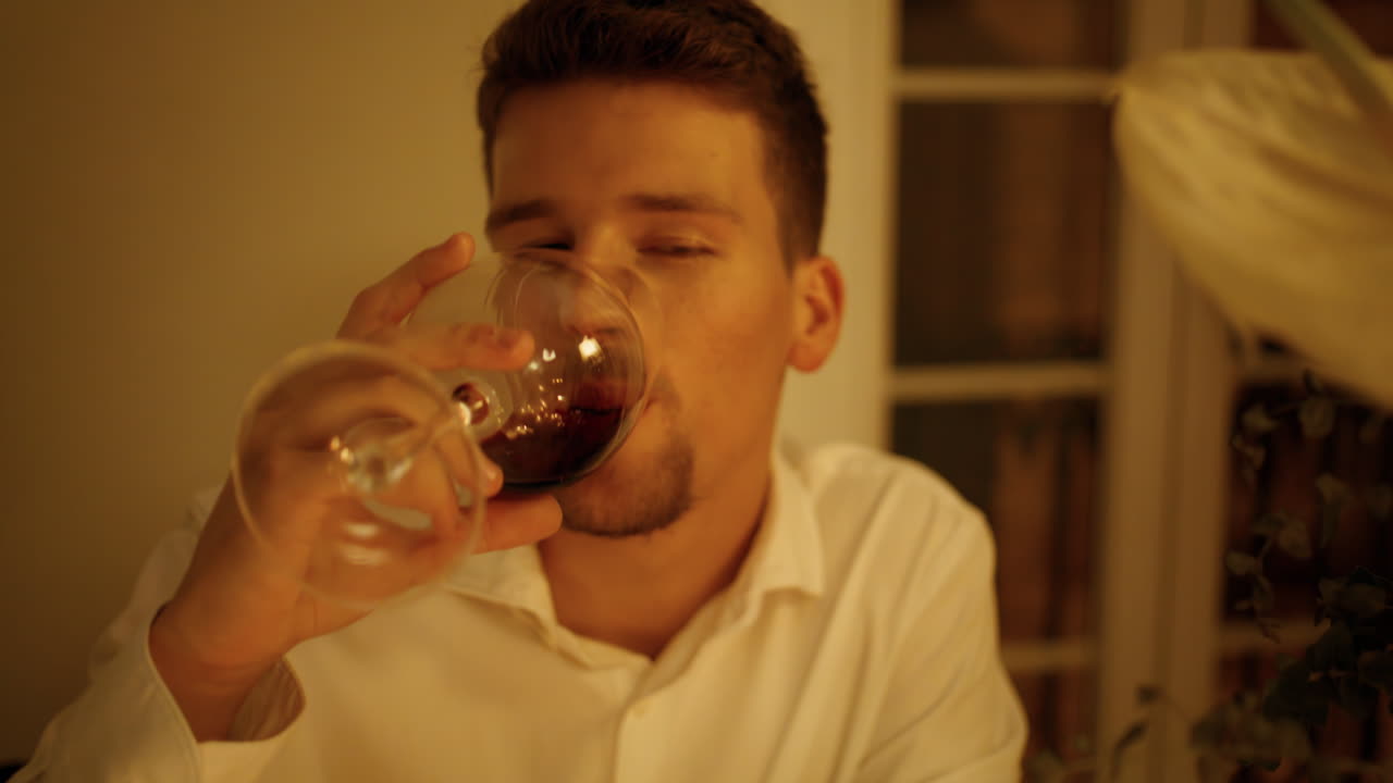 hombre guapo degustando vino en una sala de citas romántica. hombre sin afeitar bebiendo alcohol.