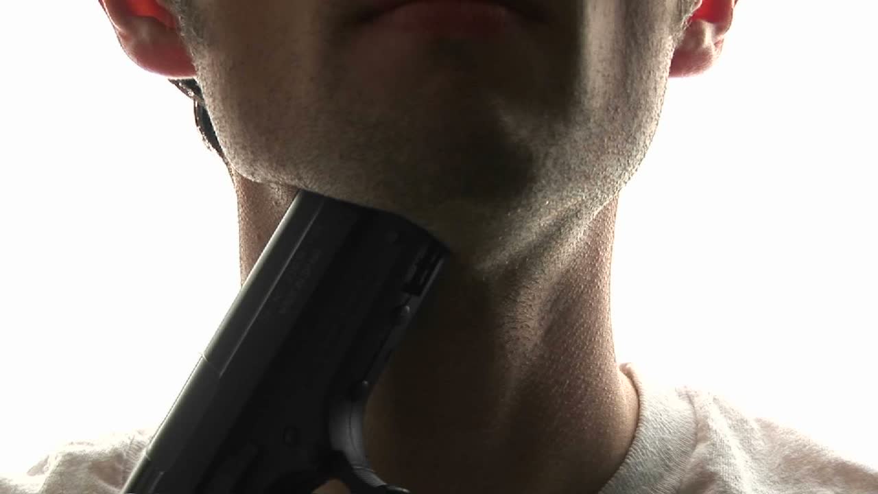 A man puts a pistol against his throat and pulls the trigger committing suicide