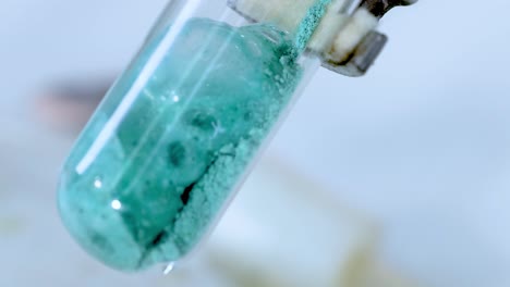 a sequence showing a green substance reacting and bubbling inside a test tube.