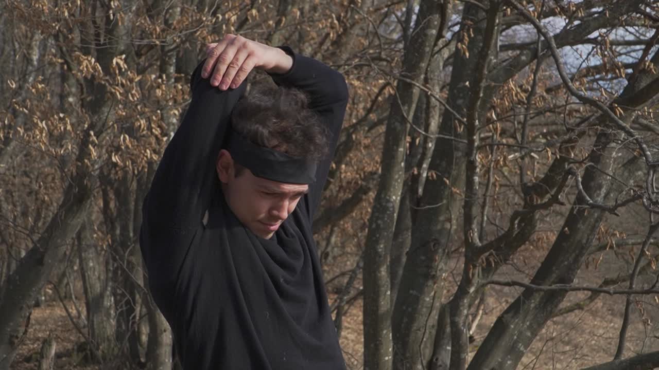 Experience serene autumn energy as a man stretches amid barren trees and crisp dry leaves. Ideal for fitness projects, seasonal visuals, and nature-themed campaigns