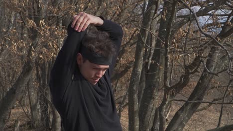 experience serene autumn energy as a man stretches amid barren trees and crisp dry leaves. ideal for fitness projects, seasonal visuals, and nature-themed campaigns