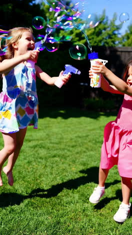 girls joyfully playing with bubbles in a sunny backyard