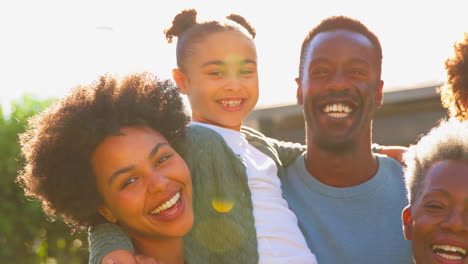 Porträt-Einer-Familie-Mit-Mehreren-Generationen-Draußen-Im-Heimischen-Garten-Vor-Der-Gleißenden-Sonne