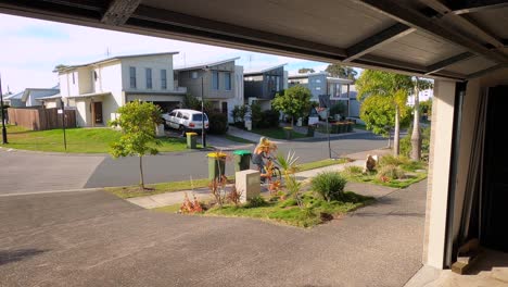 as the garage door goes up, a man rides his bike down a driveway and onto a suburban footpath and forgets to lock up