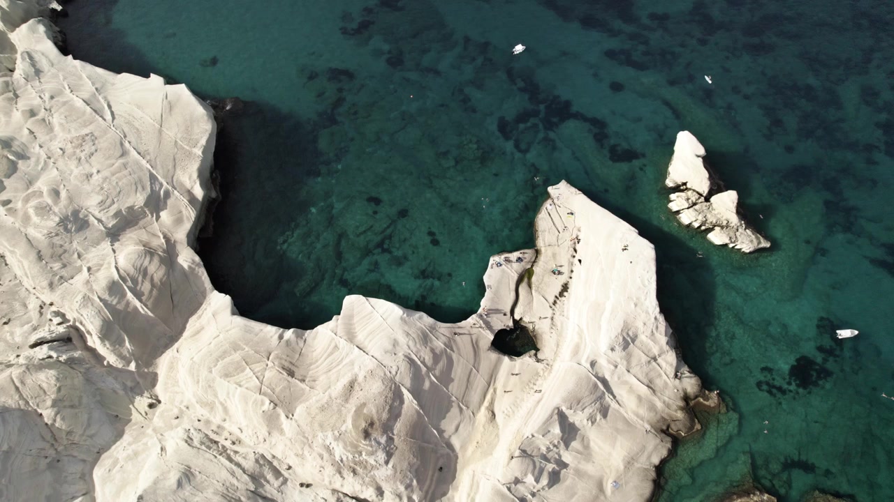 Betagende hvite klipper ruver over levende turkisblått vann i Middelhavet. Sommer i Milos, Hellas 4k