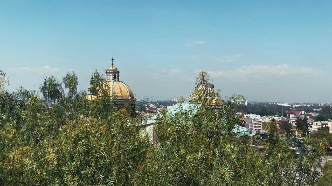 Golden church domes and the modern city skyline are partially visible through trees in Mexico City, showing the mix of historic and urban architecture
