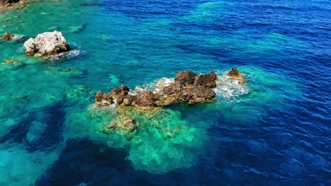 hermoso paisaje marino con olas salpicando rocas en la playa de agia eleni, grecia - órbita aérea