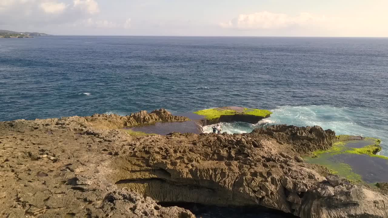 increíble vista aérea vuelo lentamente inclinado hacia abajo vuelo de drones grandes olas del océano rompiendo en las rocas de la lágrima del diablo en lembongan indonesia