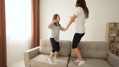 mother and daughter jumping on couch