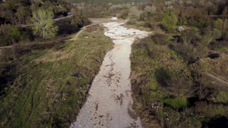 dramatic aerial ascend over dry river surrounded by forests