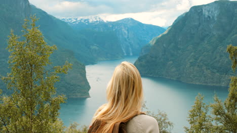 mujer disfrutando de la vista de un fiordo noruego