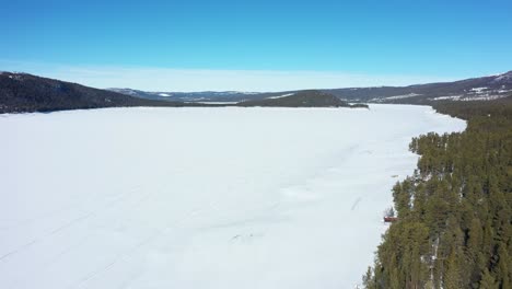 Flying-over-massive-snow-covered-freshwater-lake-Tunhovdfjord-looking-over-island-at-Palsbufjord-in-Nore-and-Uvdal-Norway---Natural-magazine-used-for-hydroelectricity-by-Statkraft-Norway