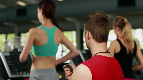 Männlicher-Trainer-überprüft-Die-Leistung-Des-Laufbands