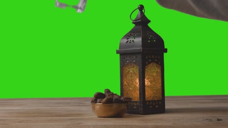 a tracking shot of lantern water and dates in front of a green screen