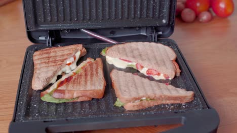 Sliced-lettuce-tomato-cheese-panini-sandwich-cooked-on-electric-grill,-panning