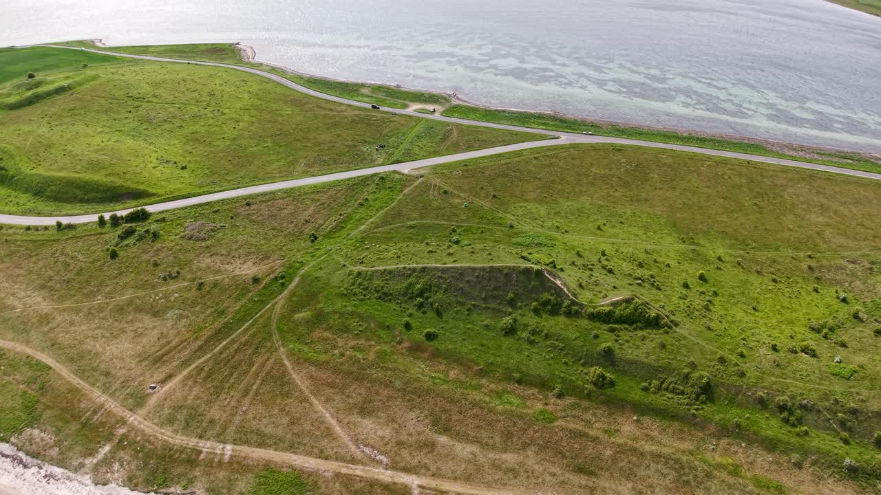 Aerial drone footage of Dragsmur in Denmark, the historic Viking land crossing connecting Helgenæs to the mainland, showing grassy terrain and coastal views