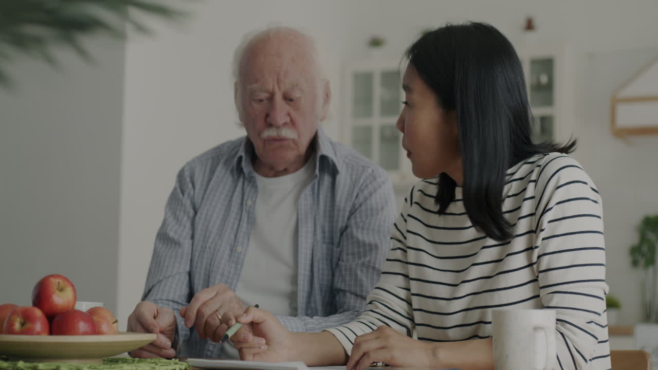 Elderly Man and Daughter Working Together on Paperwork