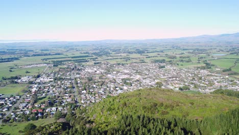 flying parallel to a small town with fields and mountains in the background