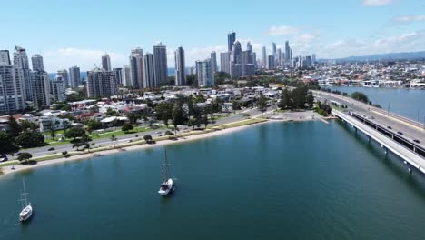 flying over a bay with sailing boats towards skyscrapers and a small beach