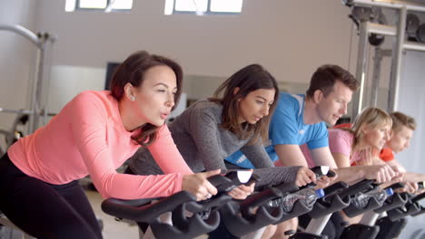 a row of people on exercise bikes in a spinning class at gym