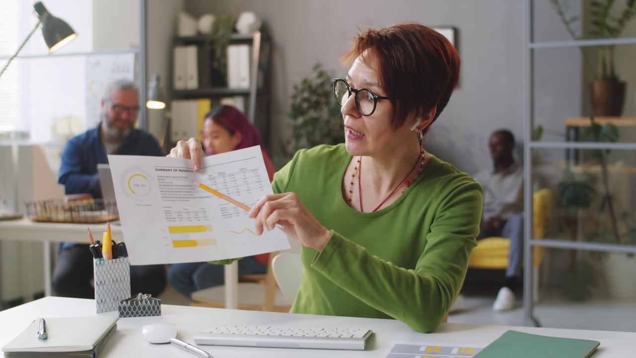 Mid-Age Businesswoman Discussing Document on Video Call