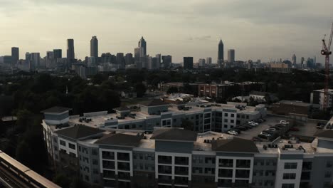 the marta metro train in atlanta georgia passes by in the foreground of an apartment complex of a gorgeous aerial shot of downtown atlanta skyline