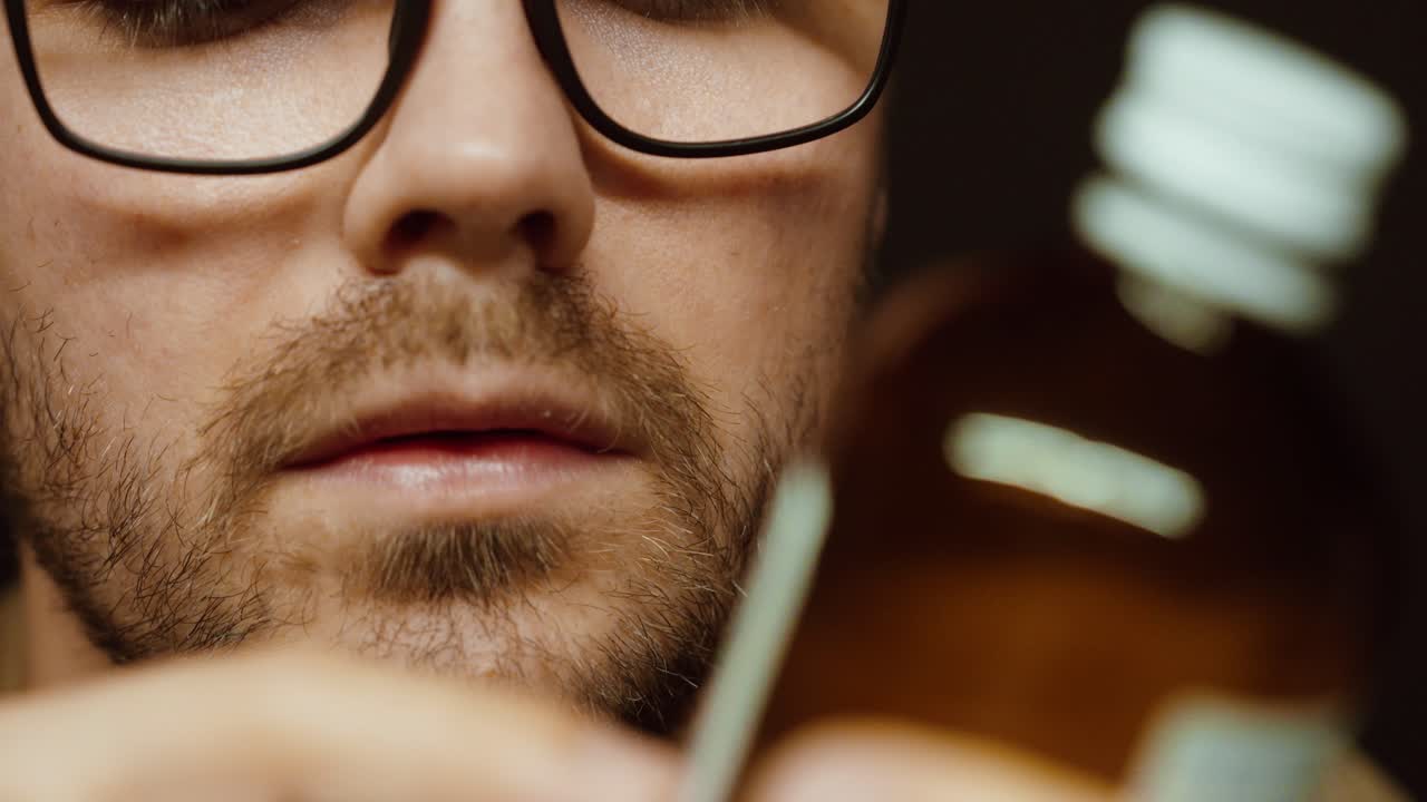 Close-up of a man with glasses carefully reading the label on a medicine bottle. Concept of healthcare, medication safety, dosage checking, and medical awareness