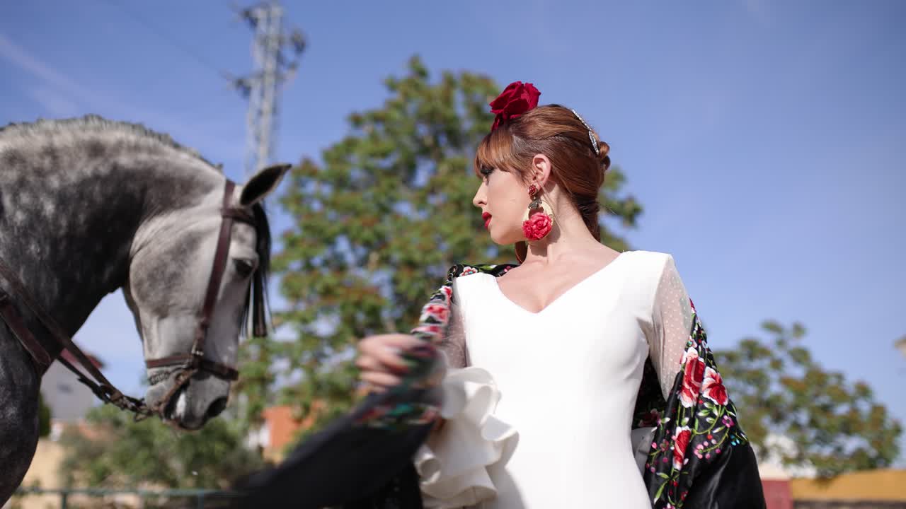 Elegante mujer española con traje tradicional posando con un caballo