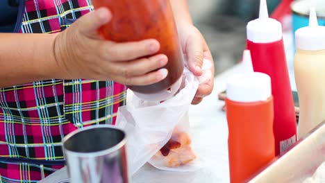 woman cutting and seasoning sausages at a stall