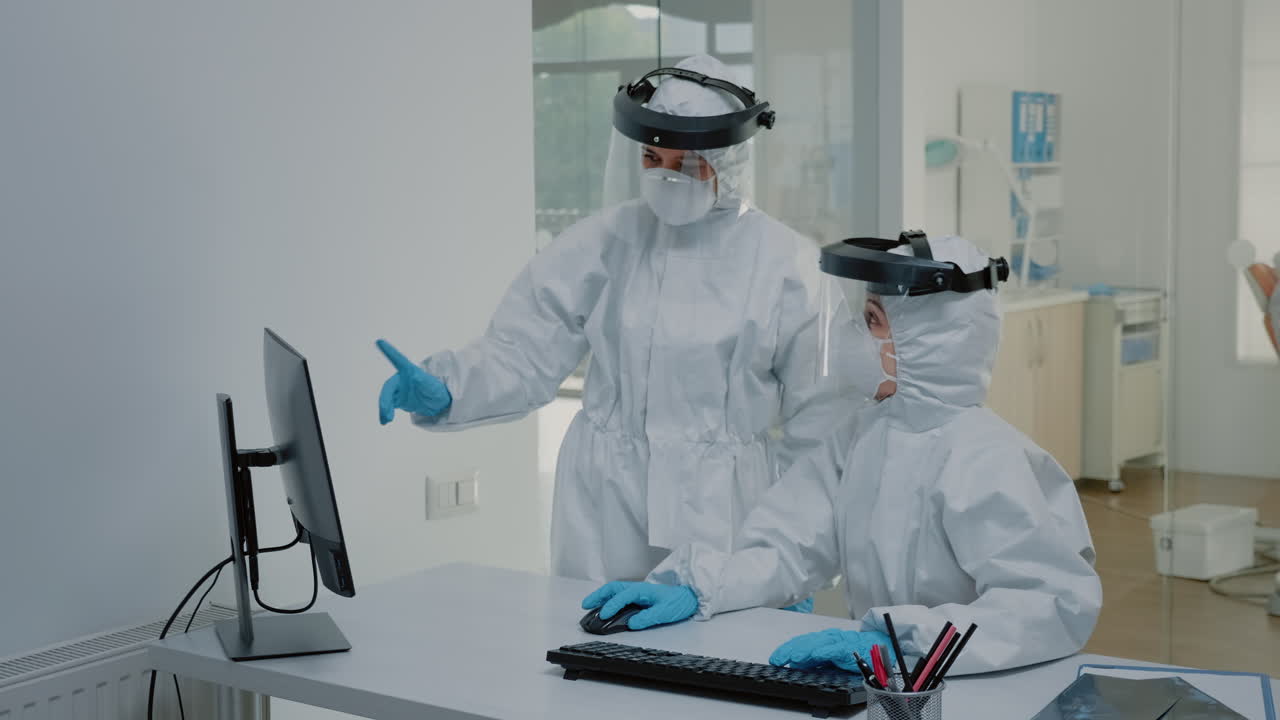 el personal de odontología con trajes de ppe discutiendo la exploración de rayos x dentales
