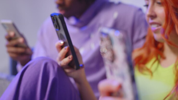 foto de estúdio de perto de jovens amigos da geração z sentados no sofá conversando e compartilhando postagens de mídia social em telefones celulares 9