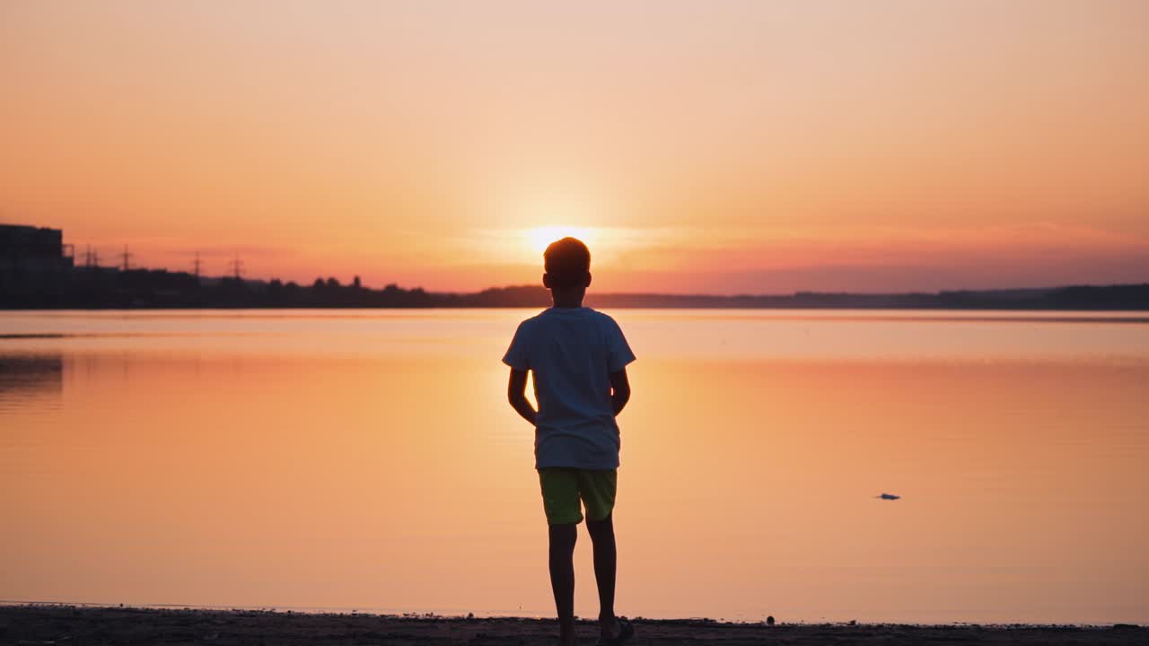 Boy walking into water. Back view of boy silhouette going into water