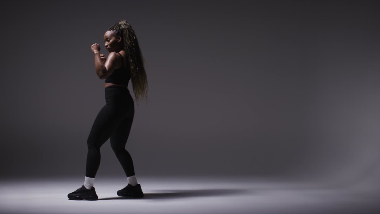 Retrato de estúdio de corpo inteiro de jovem mulher com roupa fitness treinando para boxe