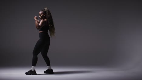 full length studio portrait of young woman wearing gym fitness clothing training for boxing exercise