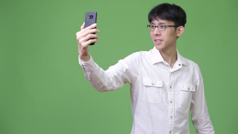 happy young asian businessman taking selfie with phone