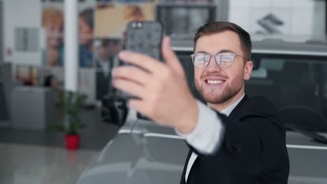 hombre guapo con gafas tomando selfie con coche en el teléfono