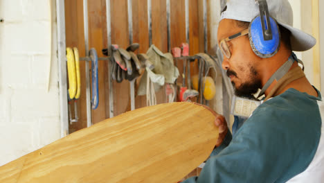 Surfboard-maker-examining-surfboard-4k