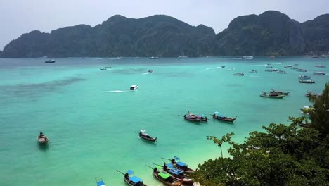 4k aerial view from bay of phi phi don full of long-tail boats, thailand