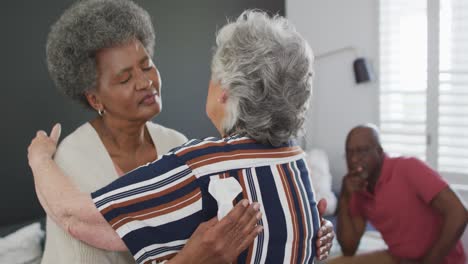 Diverse-group-of-senior-friends-giving-support-to-african-american-female-friend-on-meeting