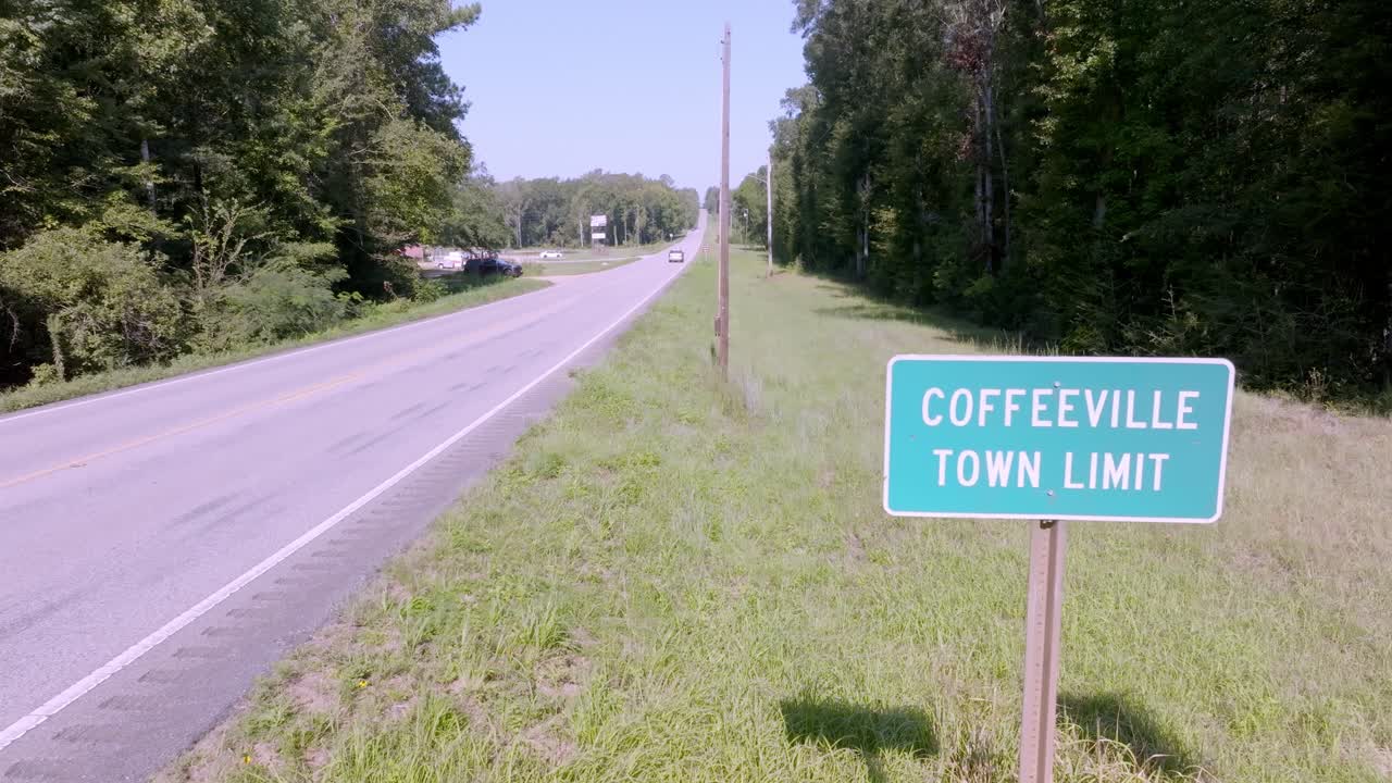 Coffeeville, Alabama town limit sign with vehicle driving by and drone video stable