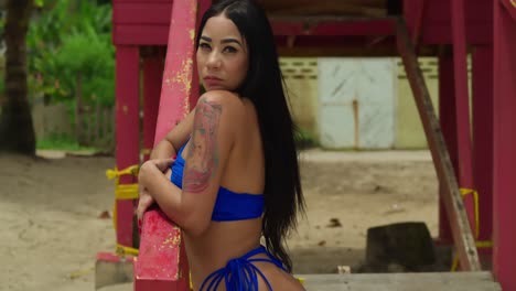 a latina exudes allure and charm in her striking blue thong bikini, captivating all who behold her along the sun-drenched expanse of maracas beach