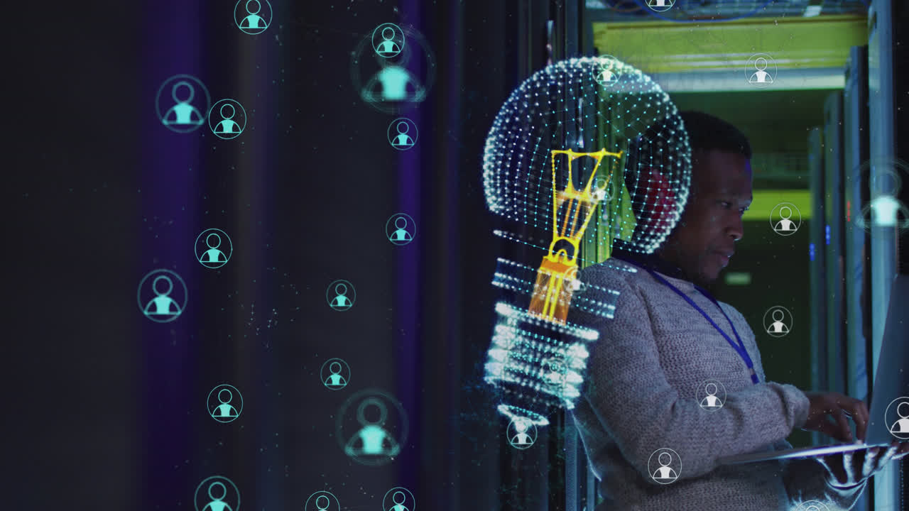 Animation of light bulb over african american man using laptop by computer server
