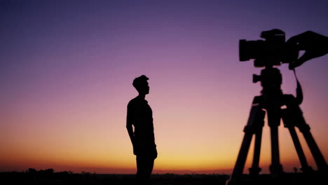 silhouetted hands adjusting a camera at sunset